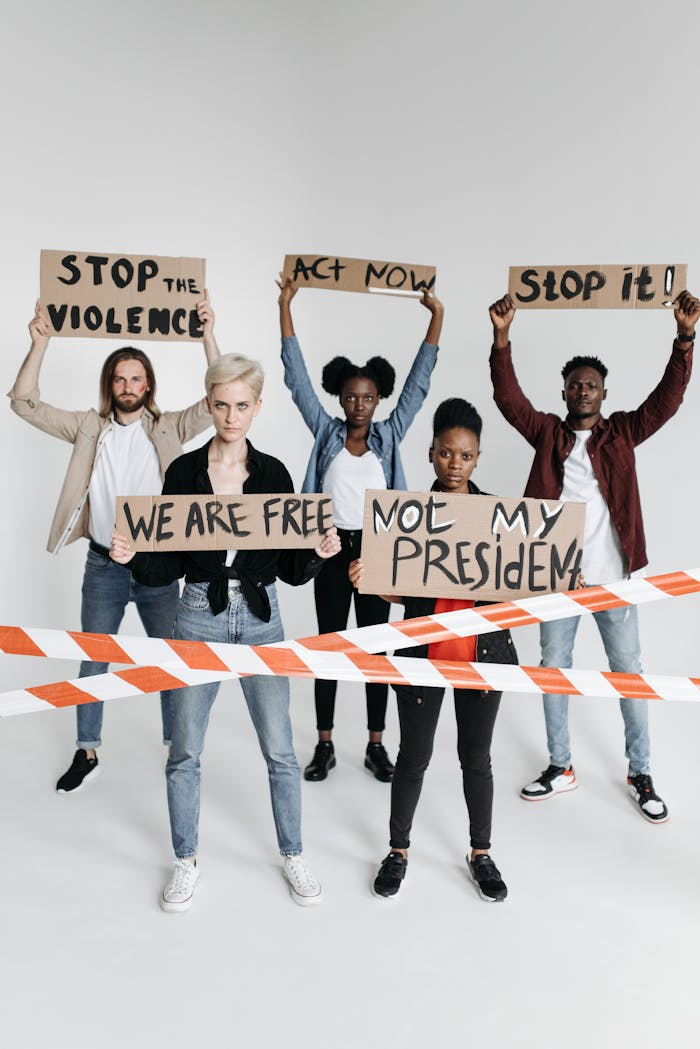 A diverse group holding protest signs advocating social change in a studio setting.